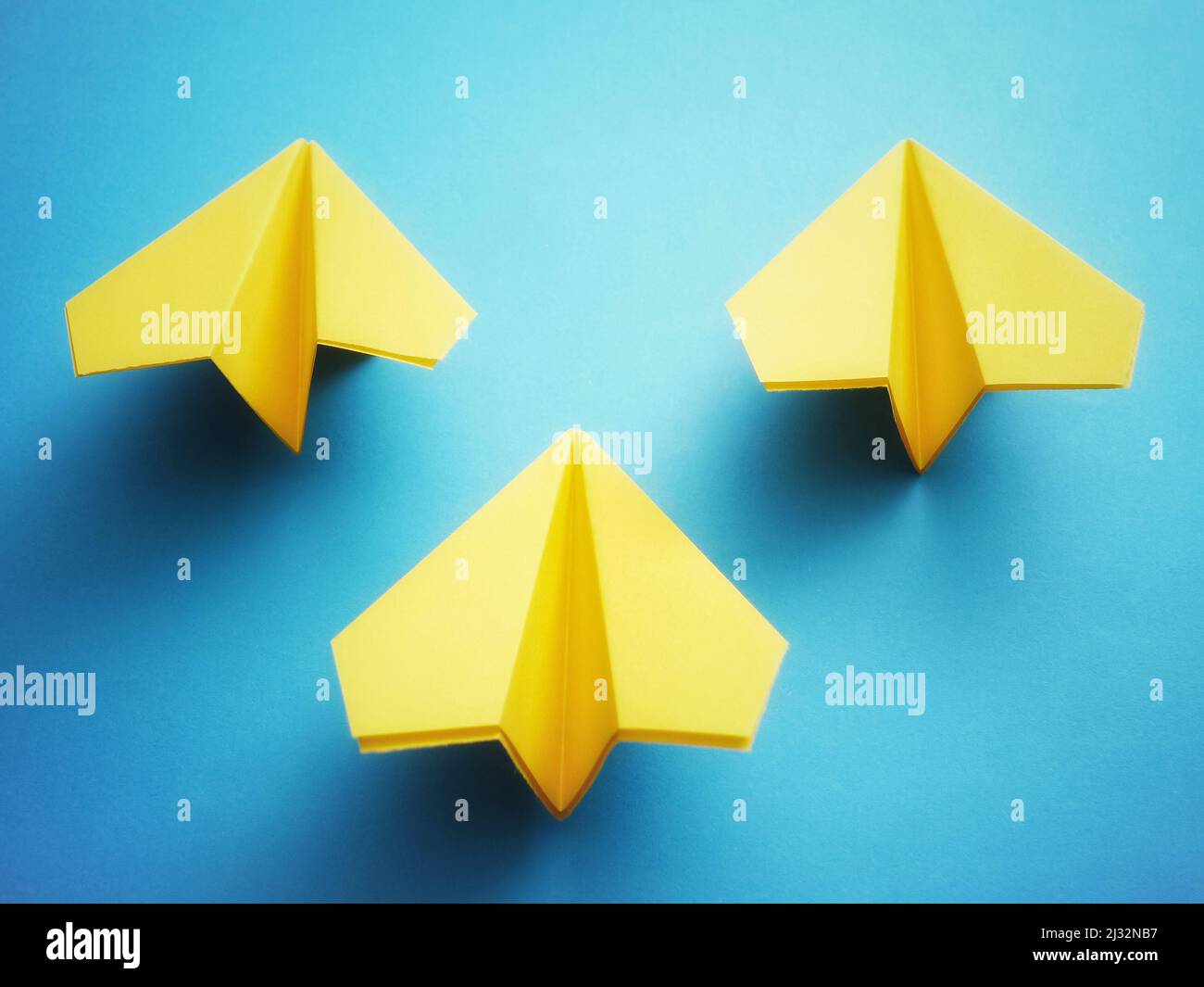 Group of three yellow paper jets on blue background. Stock Photo