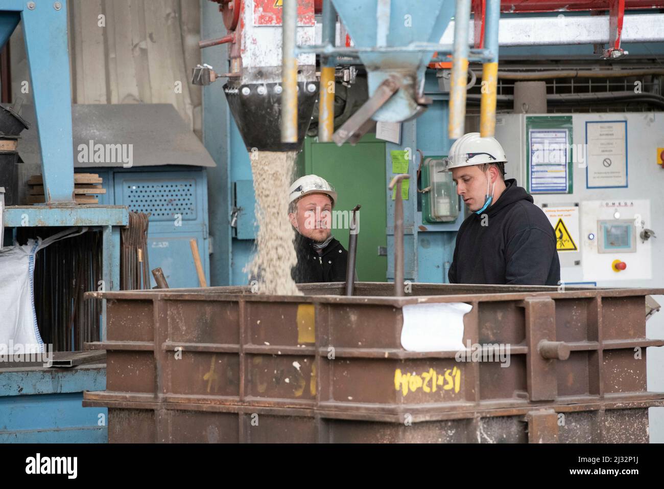 Workers prepare a casting mold with molding sand, blast furnace, steel