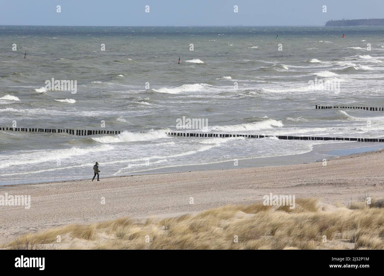 Rostock, Germany. 05th Apr, 2022. A walker walks along the beach in the seaside resort of Warnemünde in strong winds. The water level of the Baltic Sea off Warnemünde has returned to normal after the low tide of the last few days. Credit: Danny Gohlke/dpa/Alamy Live News Stock Photo