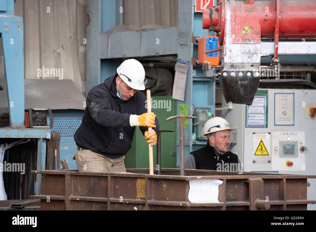 Workers prepare a casting mold with molding sand, blast furnace, molten