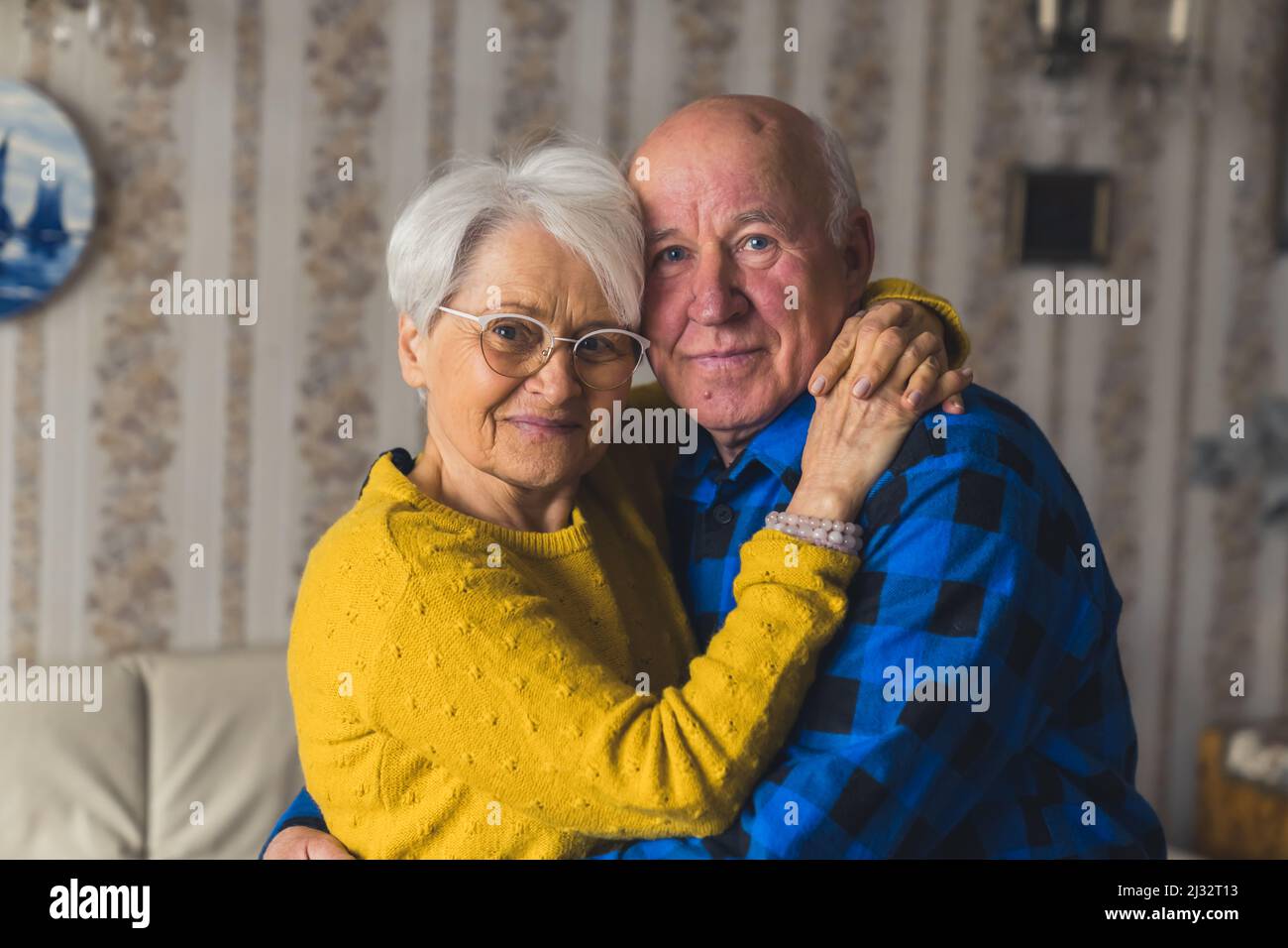 Portrait of an Caucasian European elderly couple smiling and embracing in vintage home interior. High quality photo Stock Photo