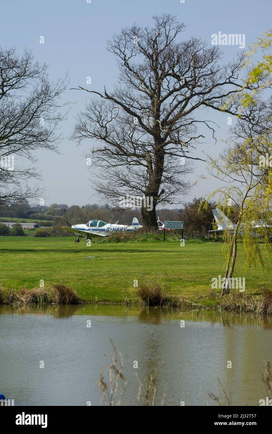 Great Oakley airfield in rural Essex, UK. Planes parked among the trees and ponds of the countryside airstrip Stock Photo