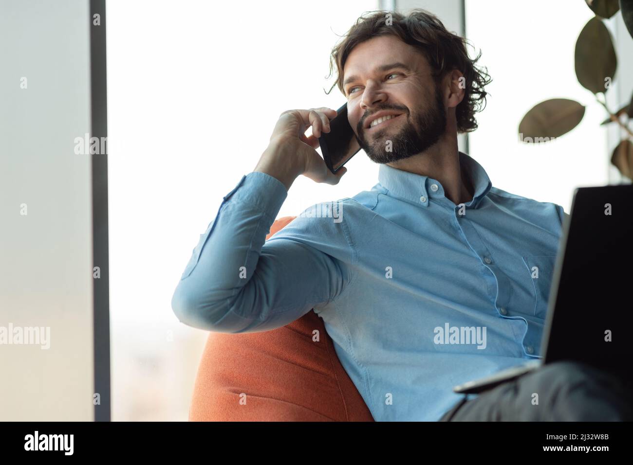 Smiling man working and talking on phone at office Stock Photo