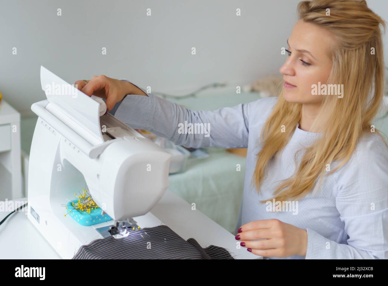 Seamstress prepare sewing machine. Tailor puts needle and spool of