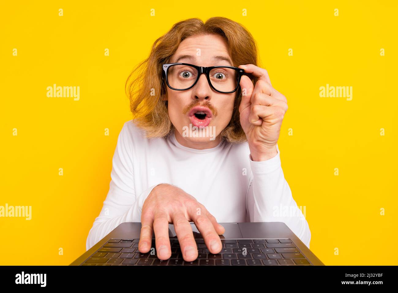 Photo of funny impressed guy dressed white shirt arm glasses writing modern device isolated yellow color background Stock Photo
