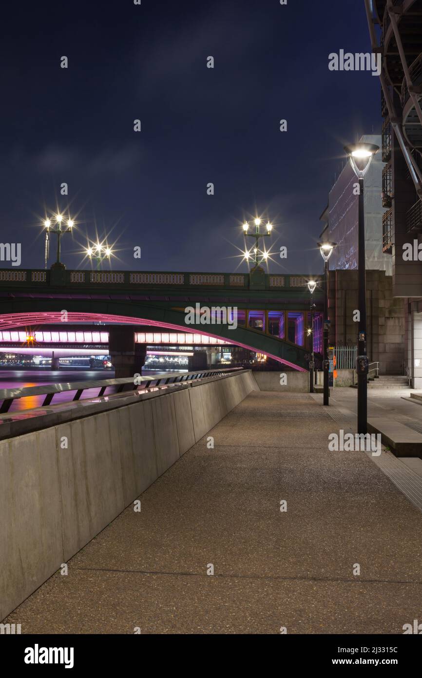 Lit Up South Bank Promenade with Street Lamps at Night Leading to Southwark Bridge, With Cannon Street Railway Bridge and London Bridge in the Rear Stock Photo