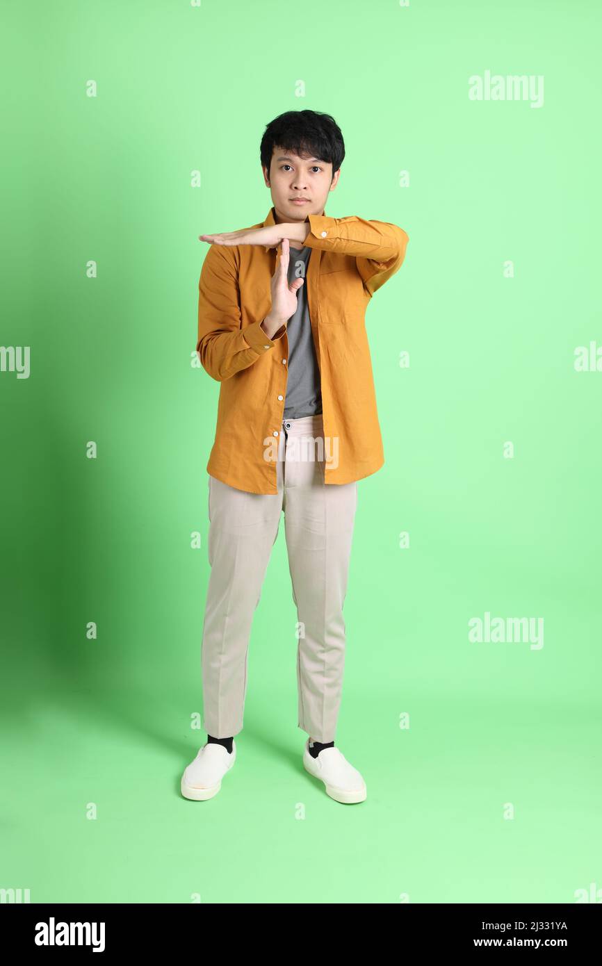 The young adult Asian man with smart casual clothes standing on the light green background. Stock Photo