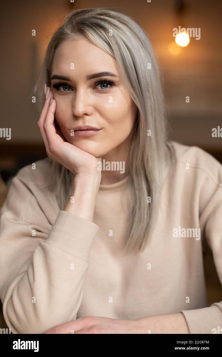 Portrait of young attractive gorgeous serious woman with long grey hair with professional make-up resting chin on hand. Stock Photo
