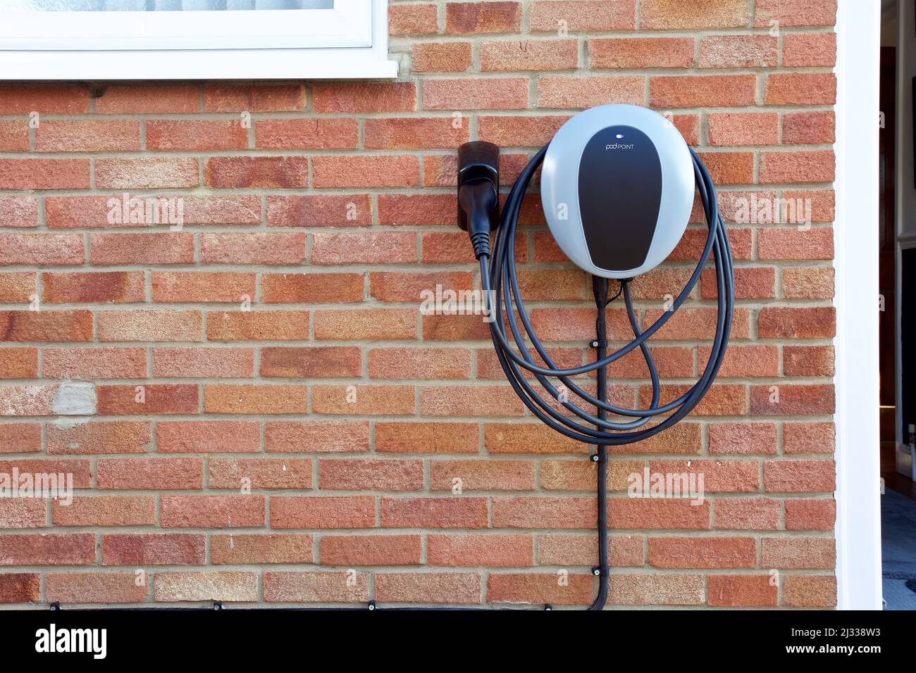 Pod Point home charger for charging an electric vehicle and is attached to an outside wall of a house. Stock Photo