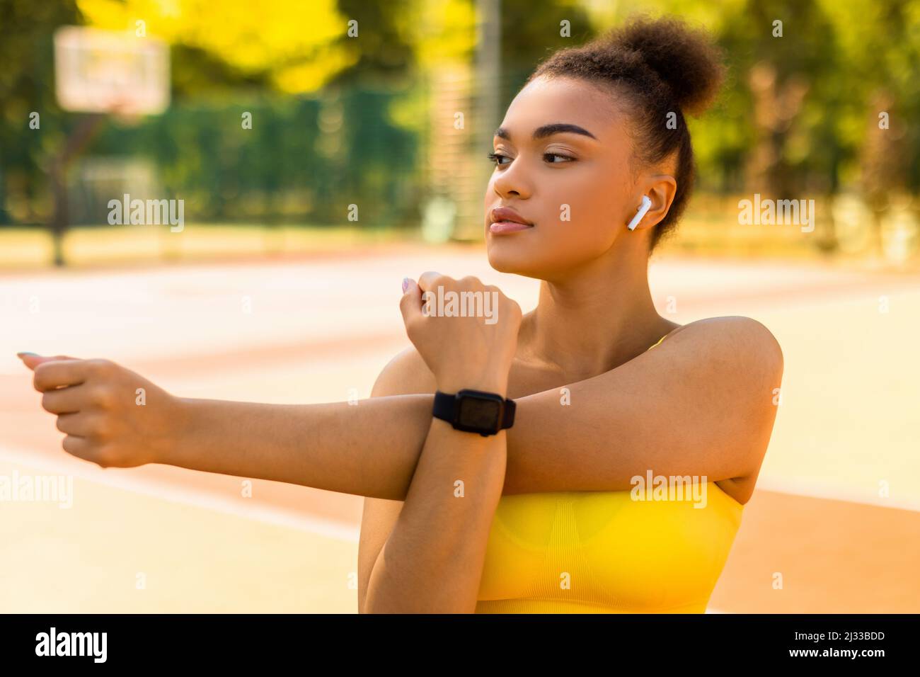 Sporty black woman in yellow sportswear stretching arms Stock Photo - Alamy