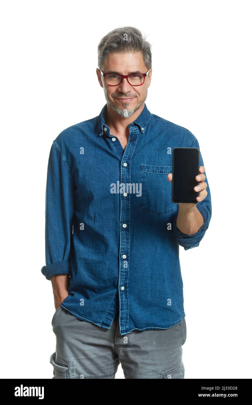 Happy older smart man in casual shirt and glasses smiling, showing phone with blank screen, ..isolated on white background. Stock Photo