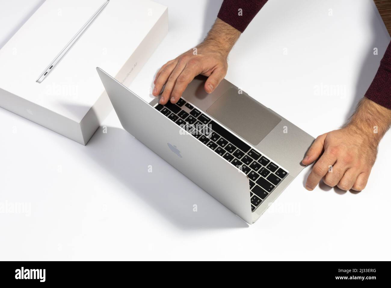 Saratov, Russia - February 26, 2022: work on Macbook Air 13 inch with M1 processor. Unpacking new Apple laptop closeup, white background. Advertising Stock Photo