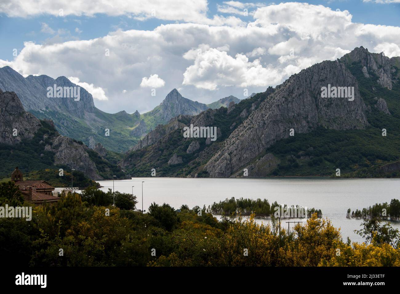 Big clouds on the sky over a mountain range with sharp peaks around a lake Stock Photo