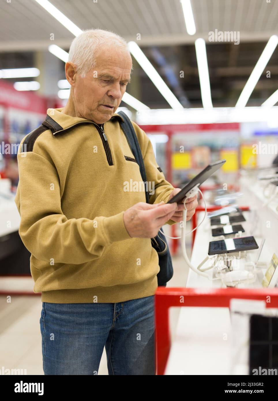 senor man pensioner buying modern tablet digital in showroom of digital electronic goods store Stock Photo