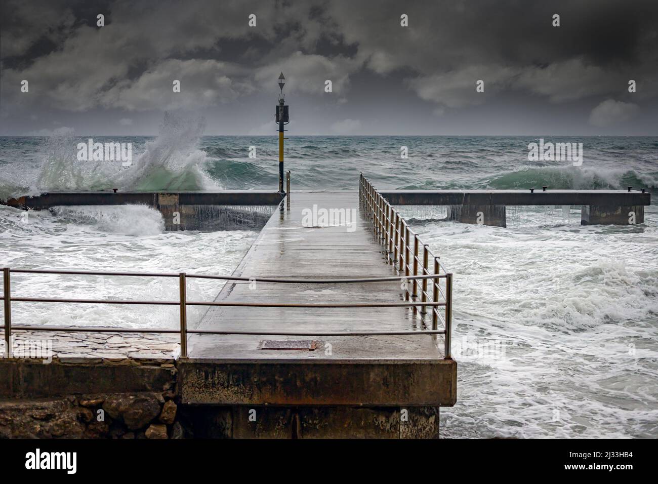 Stormy ocean waves splashing over a pier during a winters storm Stock Photo