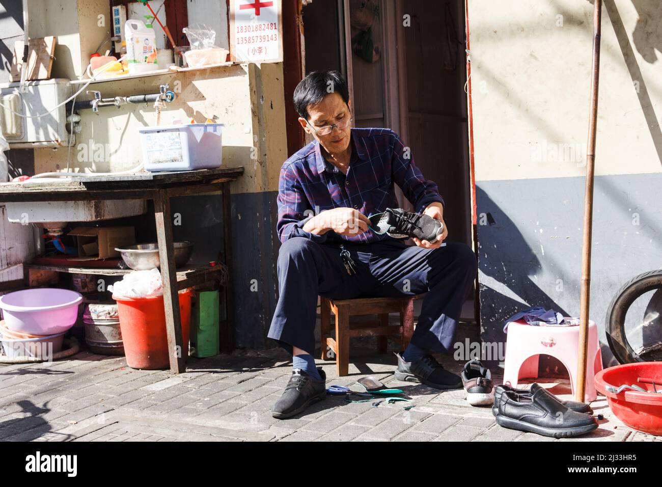 Shanghai, China- Shoe maker on street one of the oldest neighborhoods in Shanghai to be demolished Stock Photo