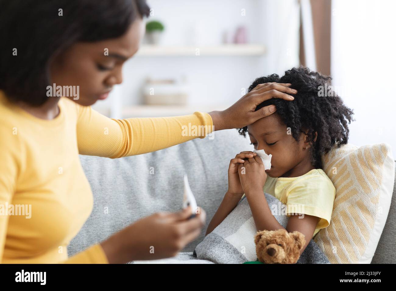 Seasonal Flu. Worried Black Mom Taking Care Of Ill Child At Home Stock Photo