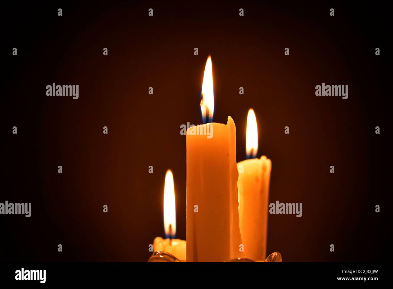 Three lighted candles on a dark background Stock Photo Alamy