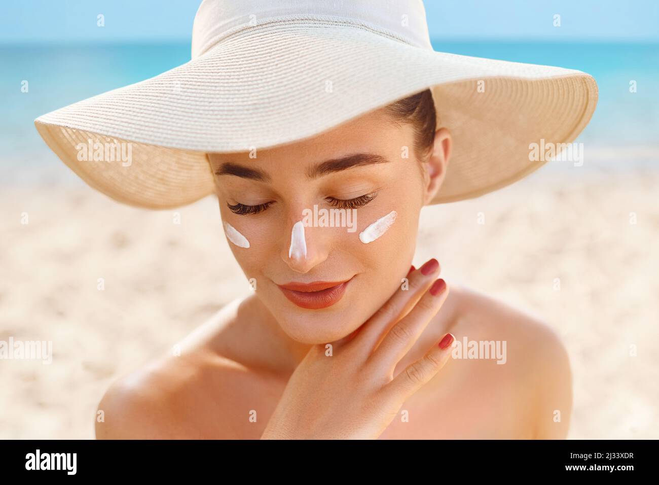 Beautiful Woman Applying on beautiful on Face. Sunscreen Solar Cream. Skin care. Sun protection Stock Photo