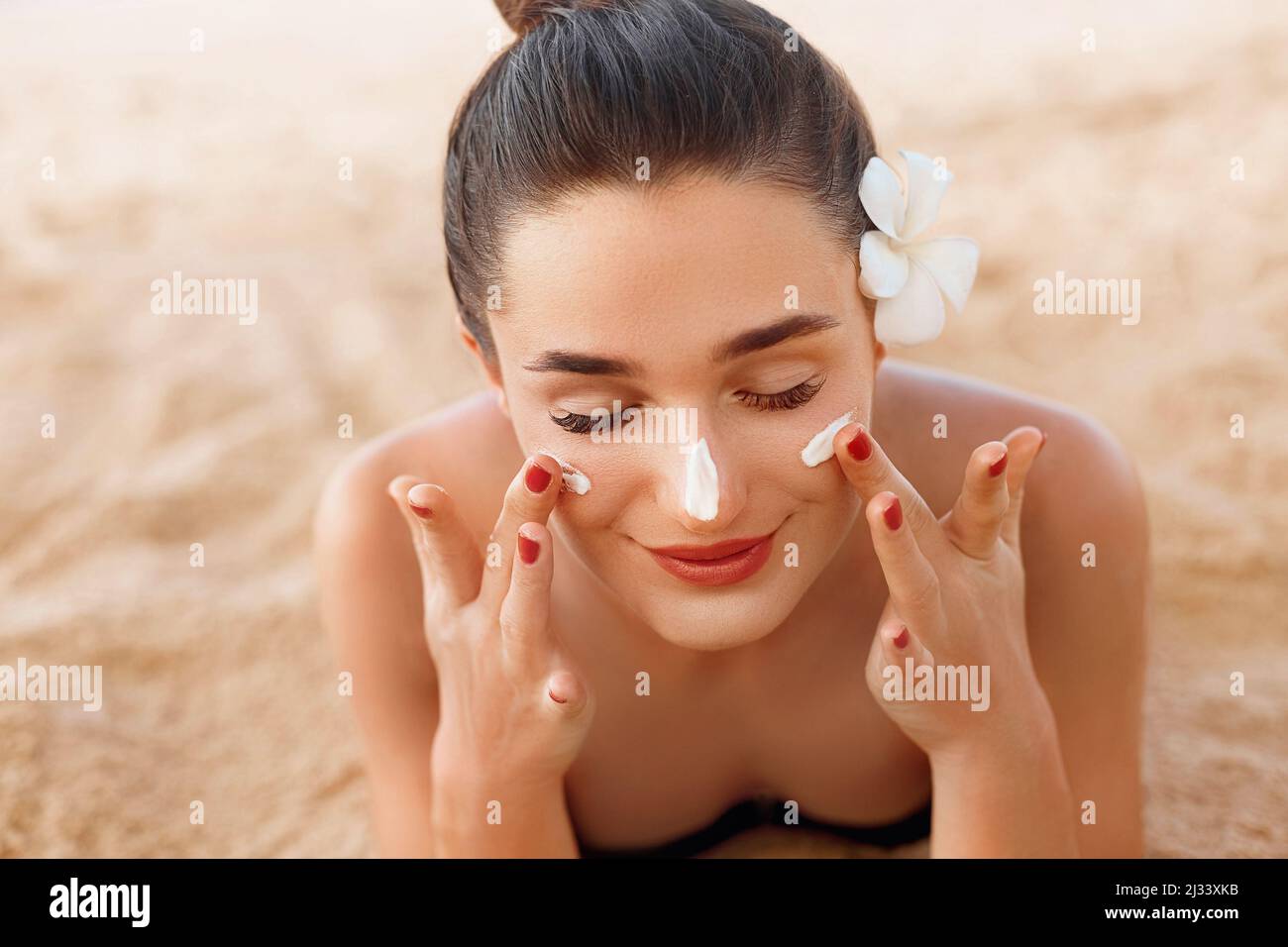 Woman smile applying sun cream  on face. Skin care. Body Sun protection. Sunscreen. Stock Photo