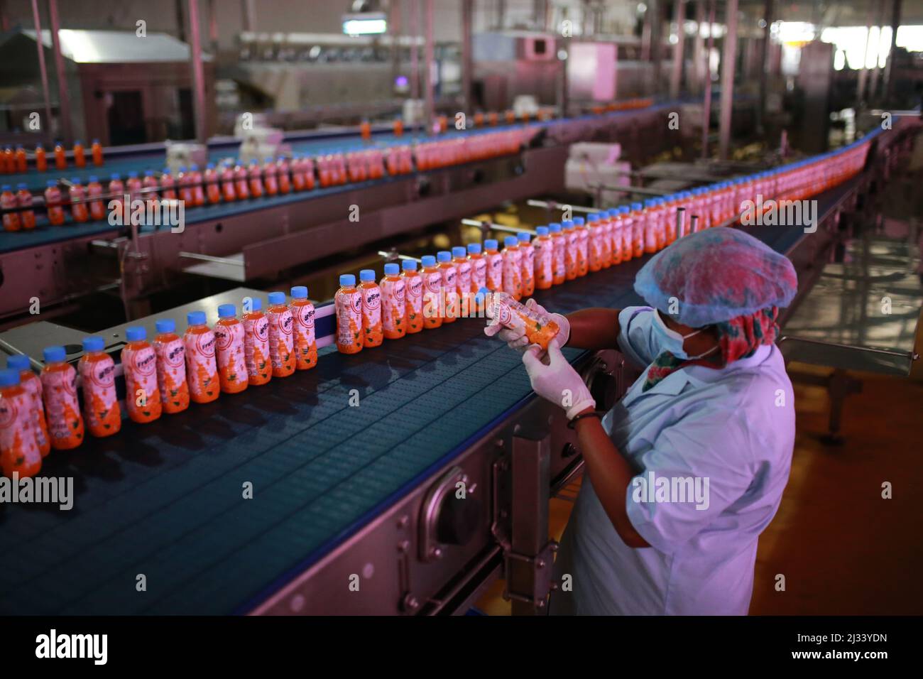 An employee quality checks a plastic bottle of soft drink are seen on