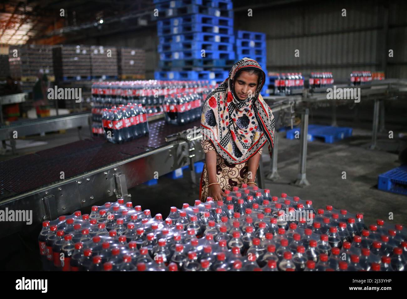 Female workers collecting newly produced soft drink bottles on an
