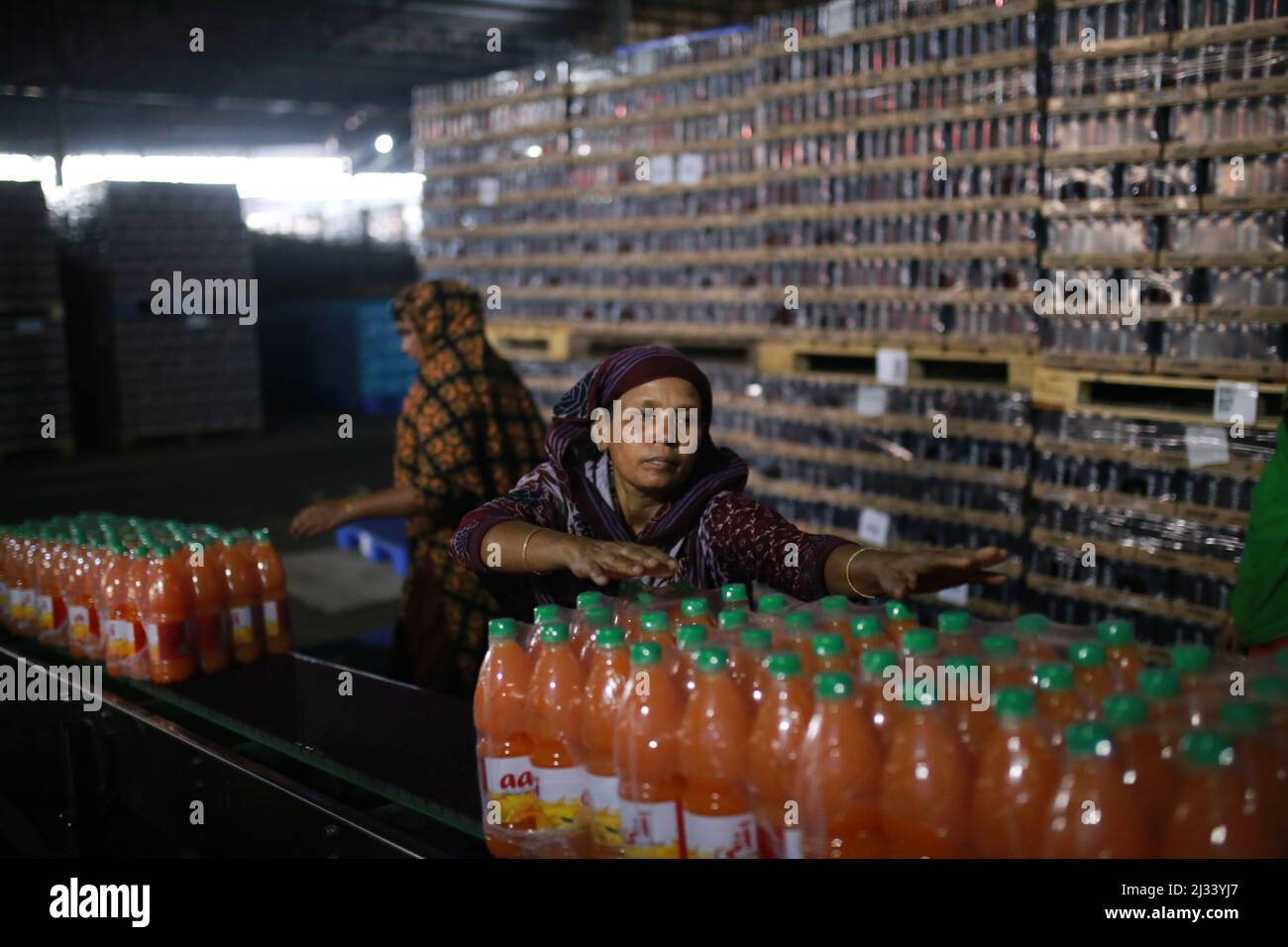 Female workers collecting newly produced soft drink bottles on an