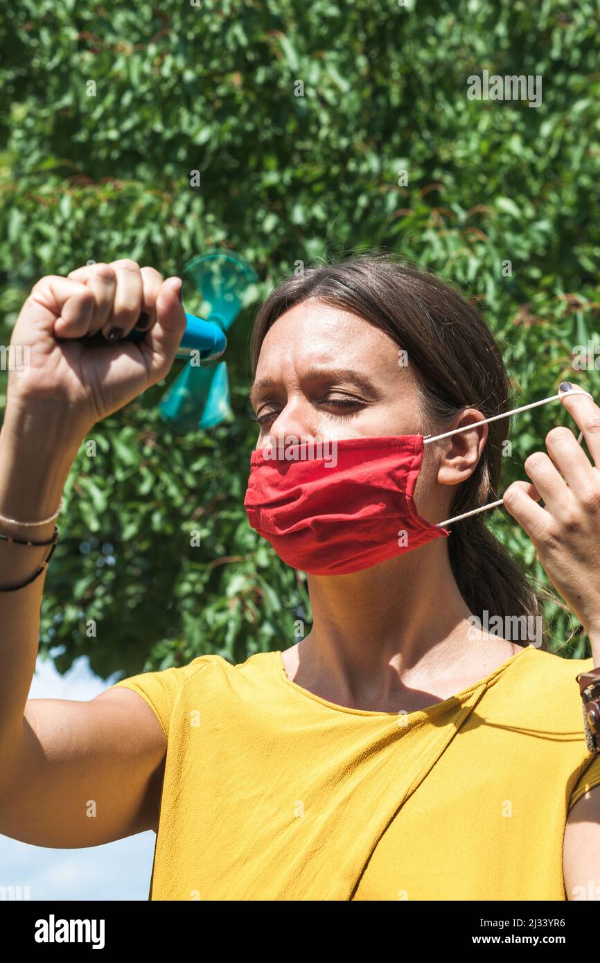 using hand held ventilator to cool down a virus protective face mask Stock Photo