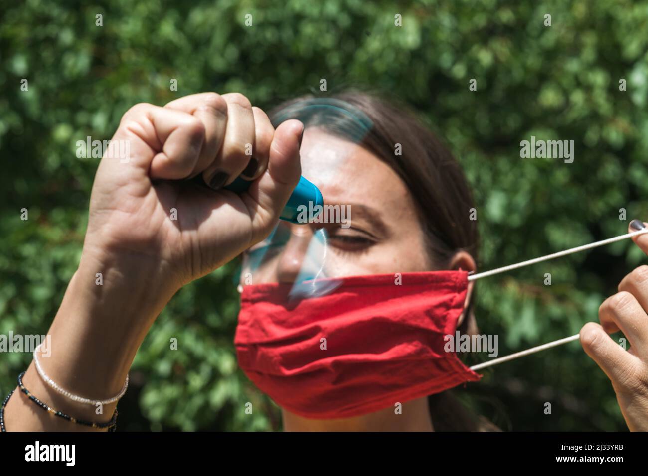 young woman cooling down with hand held ventilator while wearing a protective face mask Stock Photo