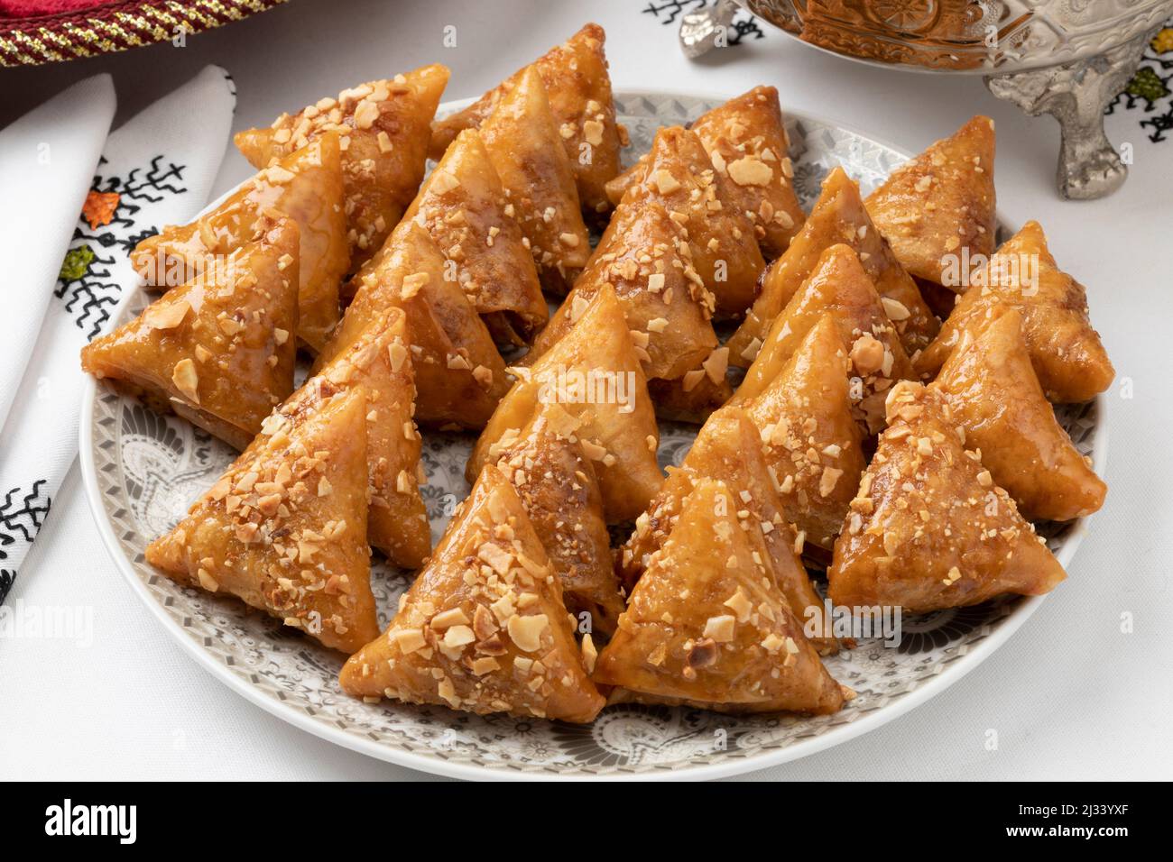 Dish with fresh traditional Almond briouats, coated in warm honey and filled with almond paste flavored with cinnamon and orange flower water close up Stock Photo