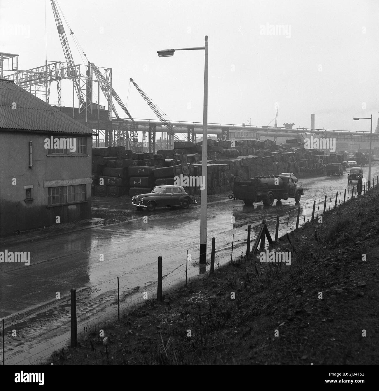 1950s, historical, road beside the giant steel plant of Abbey Works, Port Talbot, Wales, UK, where construction work in taking place. Stock Photo