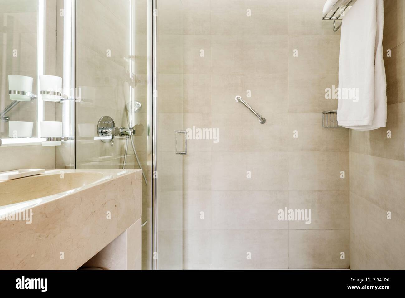 bathroom with cream colored marble sink, frameless mirror with integrated light and shower cabin Stock Photo