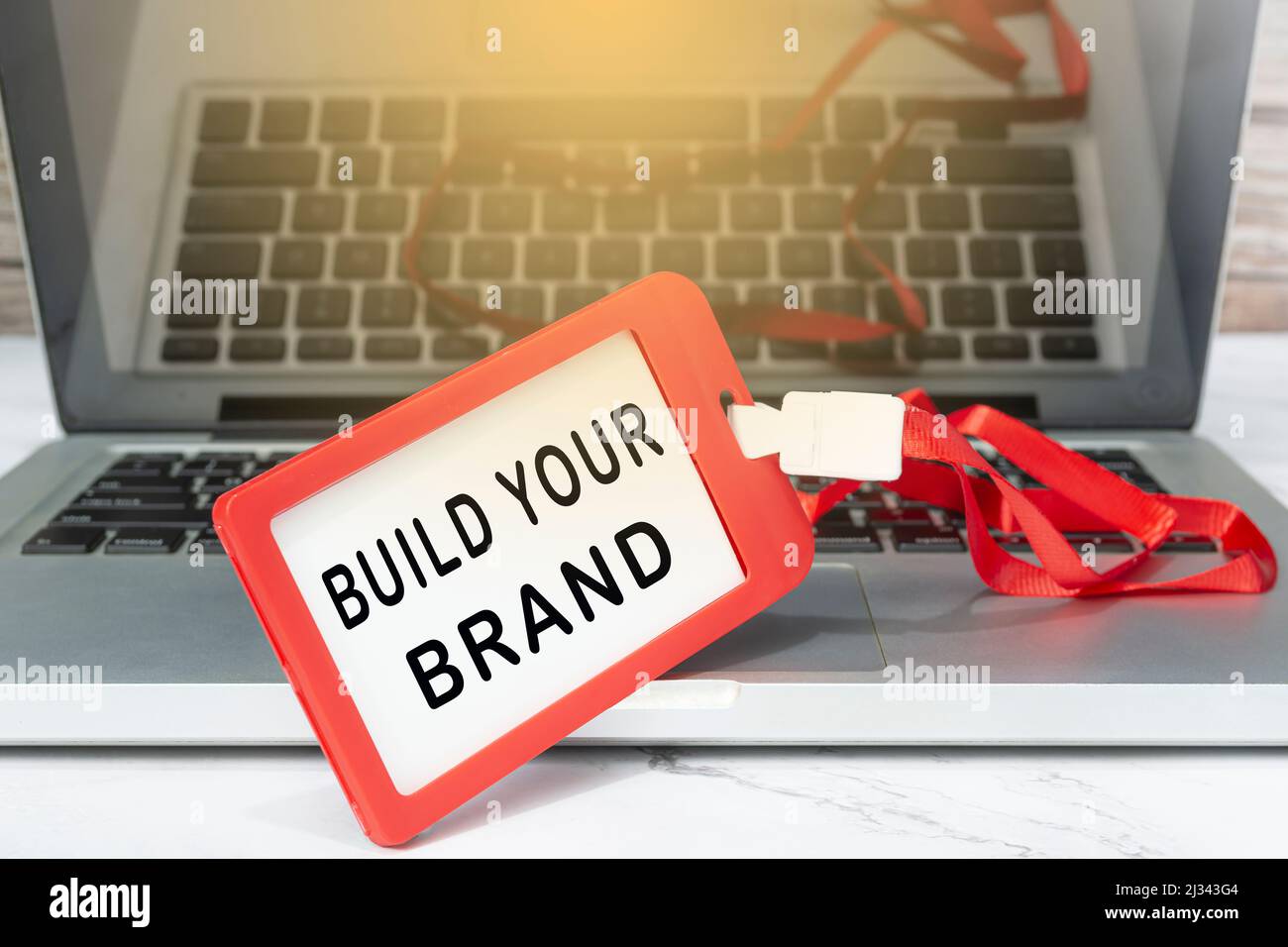 Build your brand text written on red name tag placed on a laptop or notebook.. Stock Photo