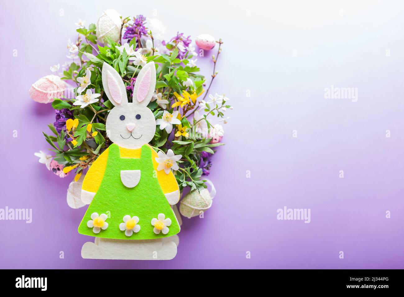 Happy Easter. Easter background with bunny spring blooming flowers and eggs on purple background. Holiday symbol. Space mockup Stock Photo