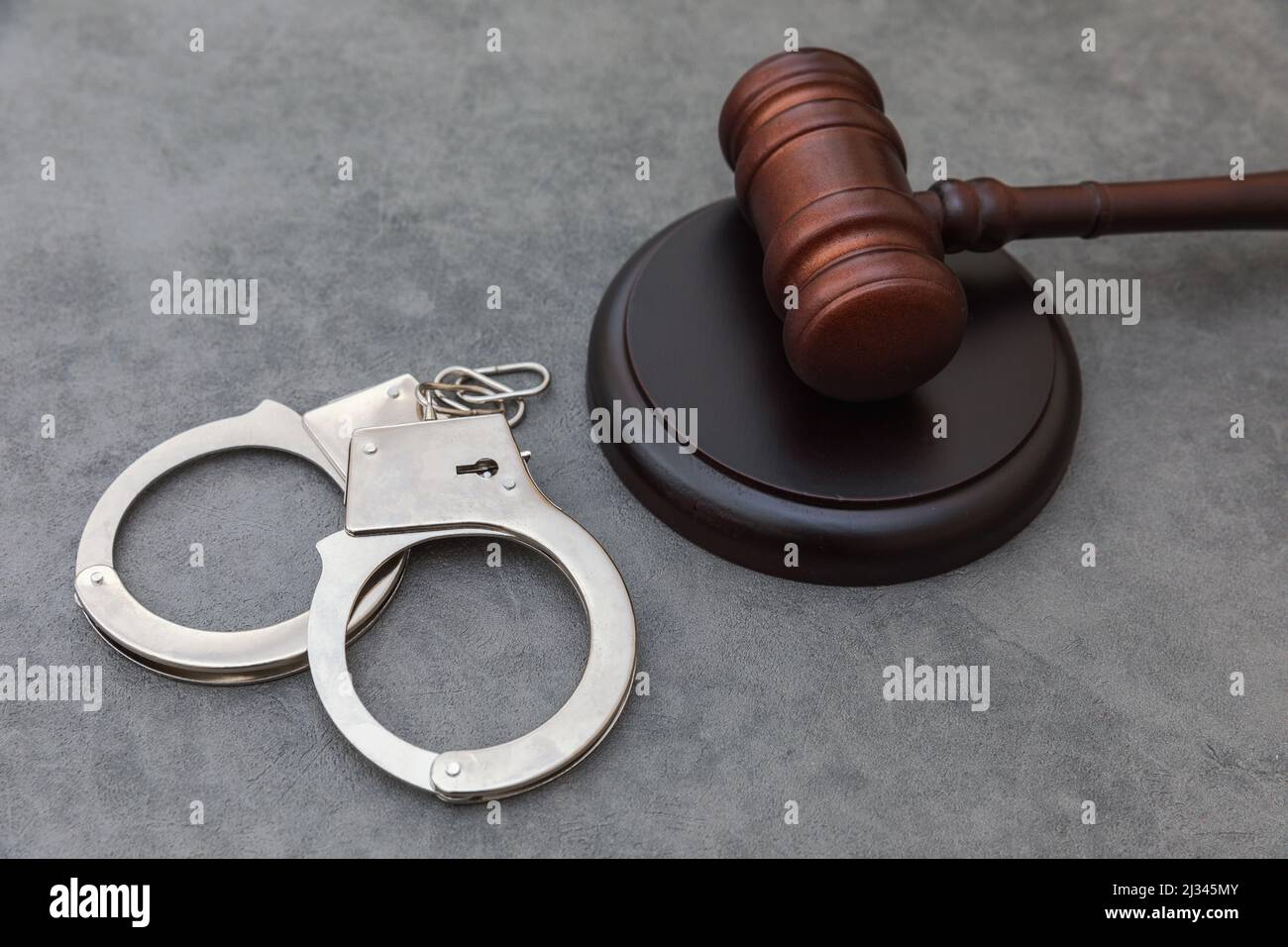 Law theme. Court of law trial in session. Judge gavel handcuffs on grey