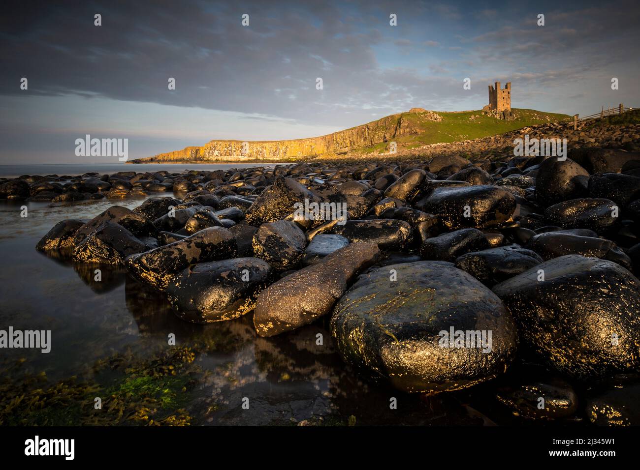 View of the stone coast at Dunstanburgh Castle ruins, Northumberland, England, Great Britain, sunset, Stock Photo