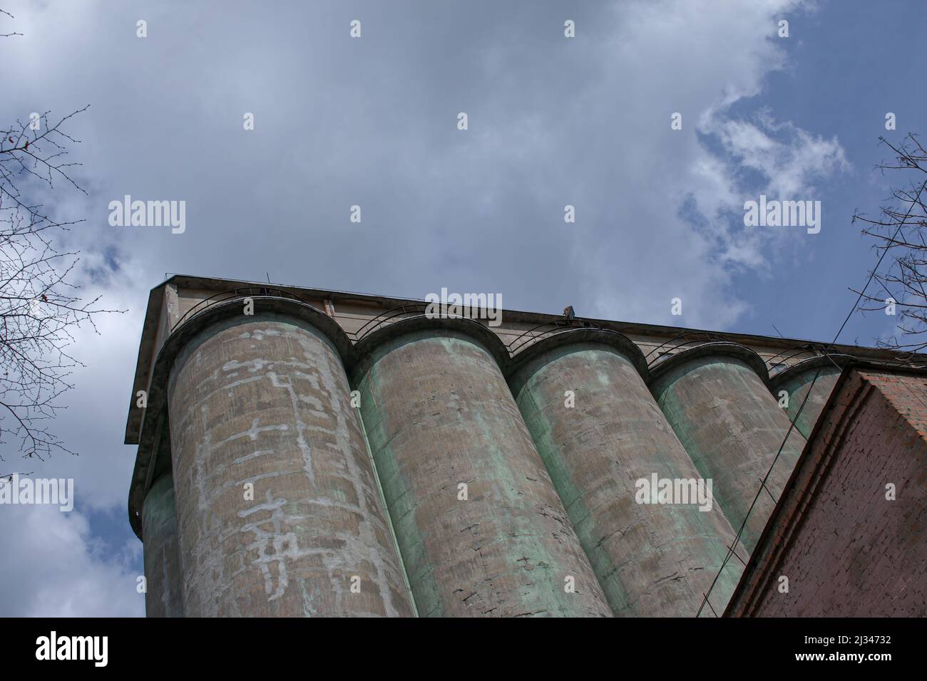 Grain elevator against a stormy sky. Large factory structure against a blue sky, low angle view. Stock Photo