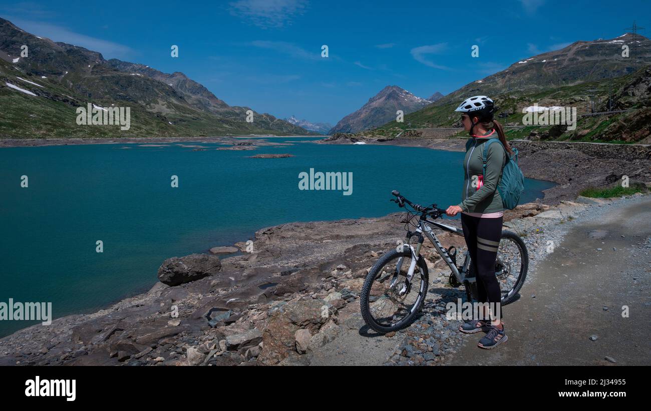 Mountain biking at the Lago Bianco reservoir at the Bernina Pass in the sun Stock Photo