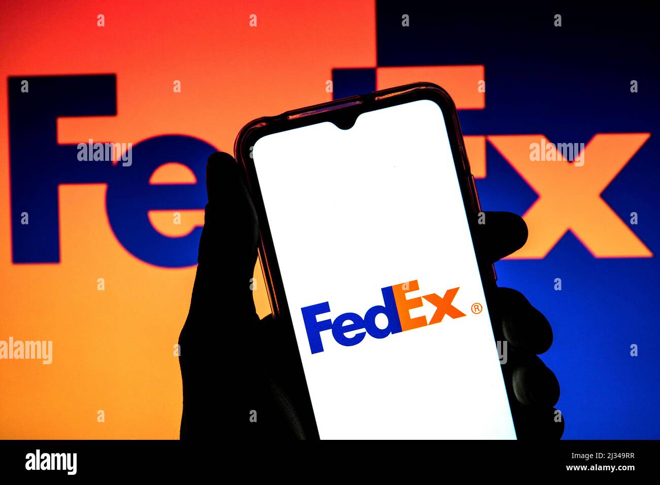 In this photo illustration a FedEx Corporation logo seen displayed on a smartphone with a FedEx Corporation logo in the background. Stock Photo