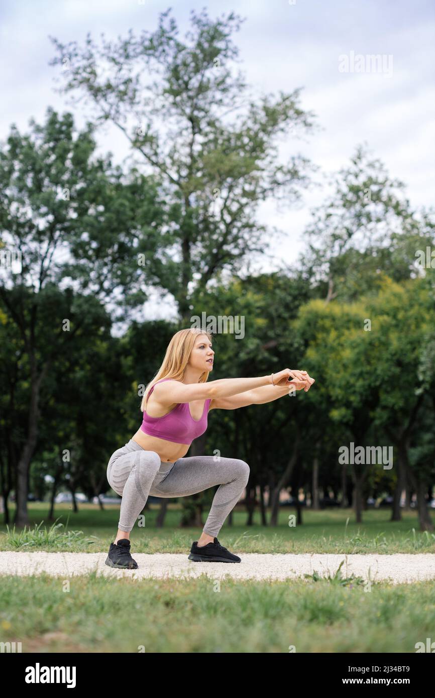 fit young woman doing squats outdoors Stock Photo