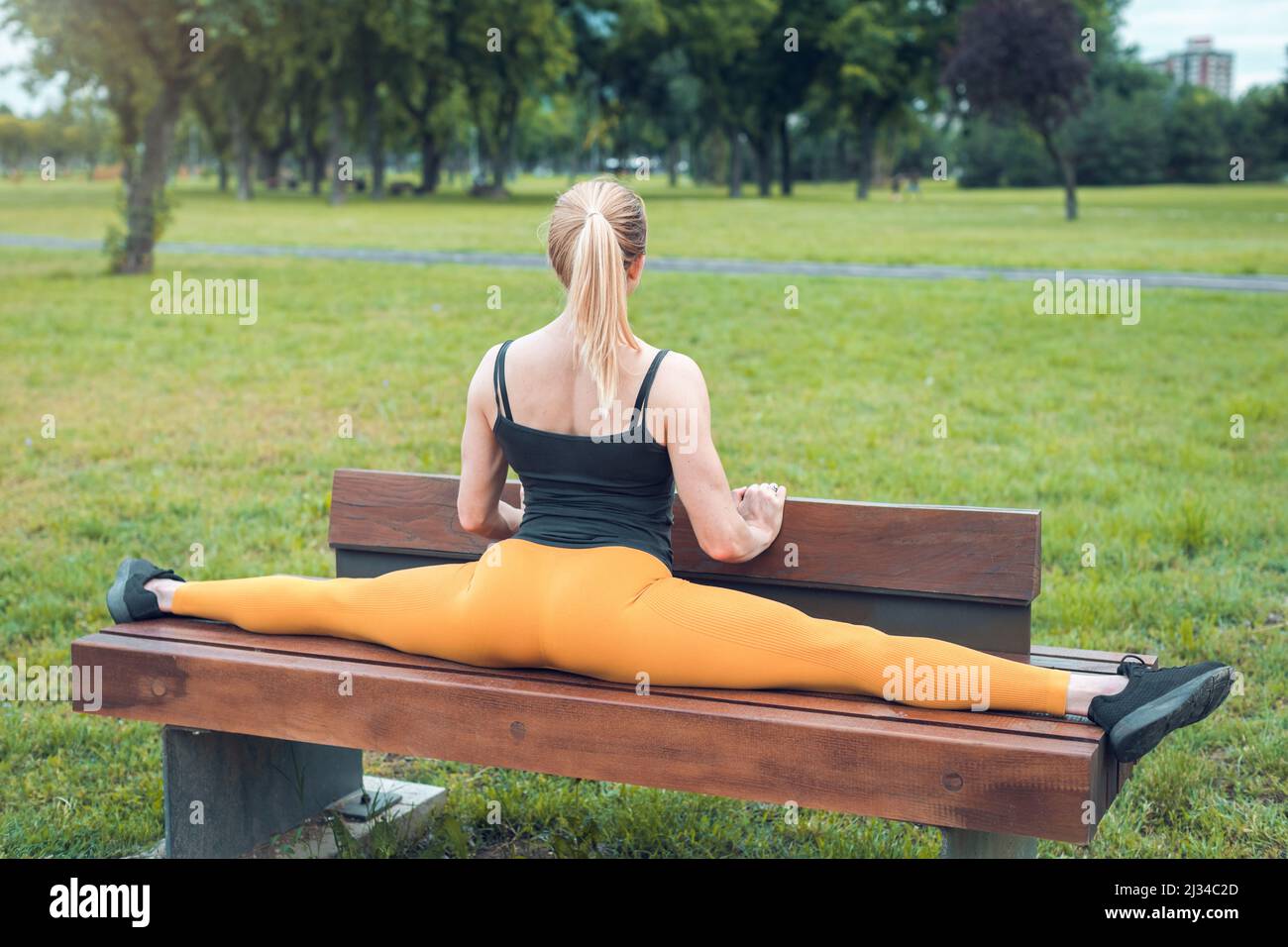 young woman doing split on a park bench Stock Photo