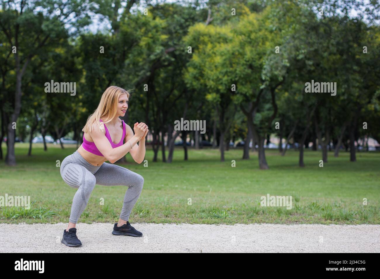 fit young woman doing squats outdoors Stock Photo