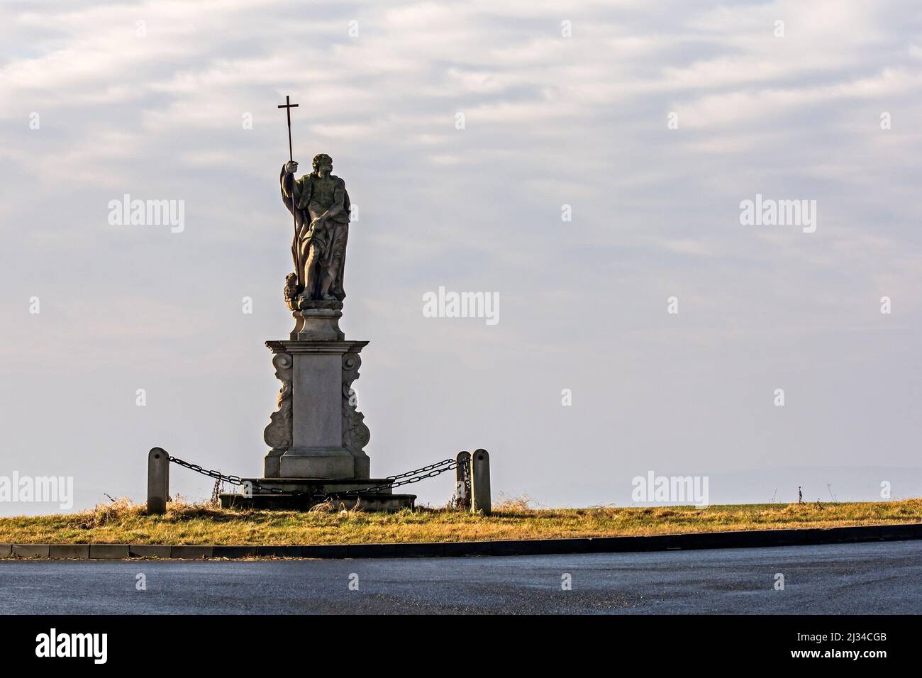 A distant view of the Passion of Christ statue on the side of the road