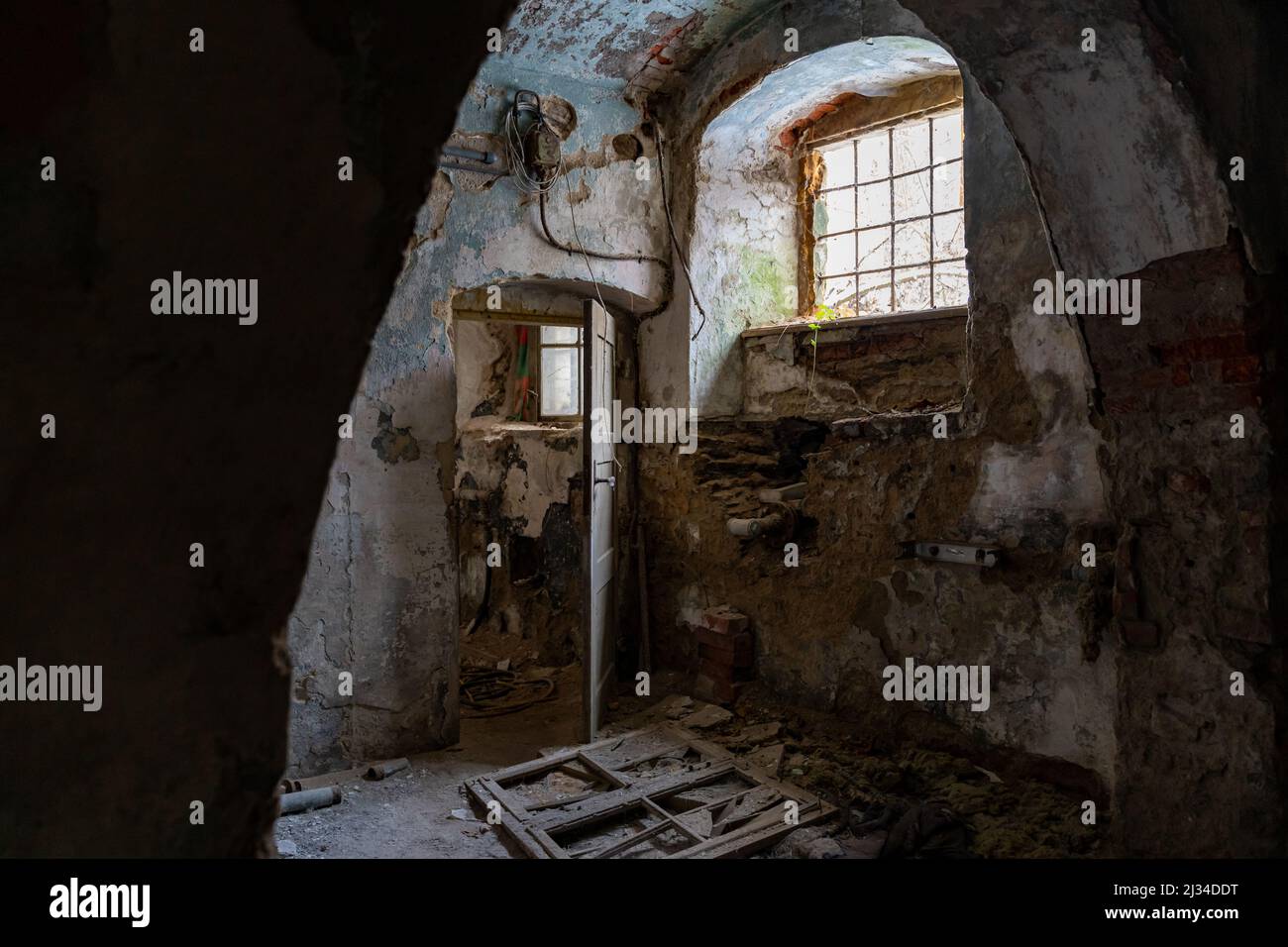 Basement of an abandoned building with damaged walls and interior in bad condition. Old ruin with paint peeling off. Eroded dangerous dirty house. Stock Photo