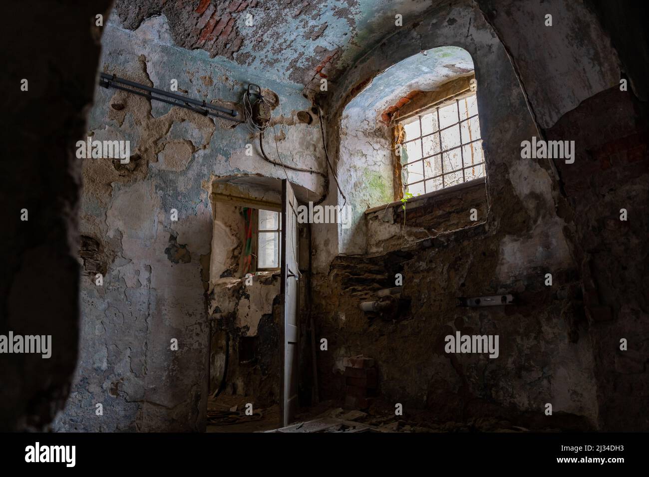 Basement of an abandoned building with damaged walls and interior in bad condition. Old ruin with paint peeling off. Eroded dangerous dirty house. Stock Photo