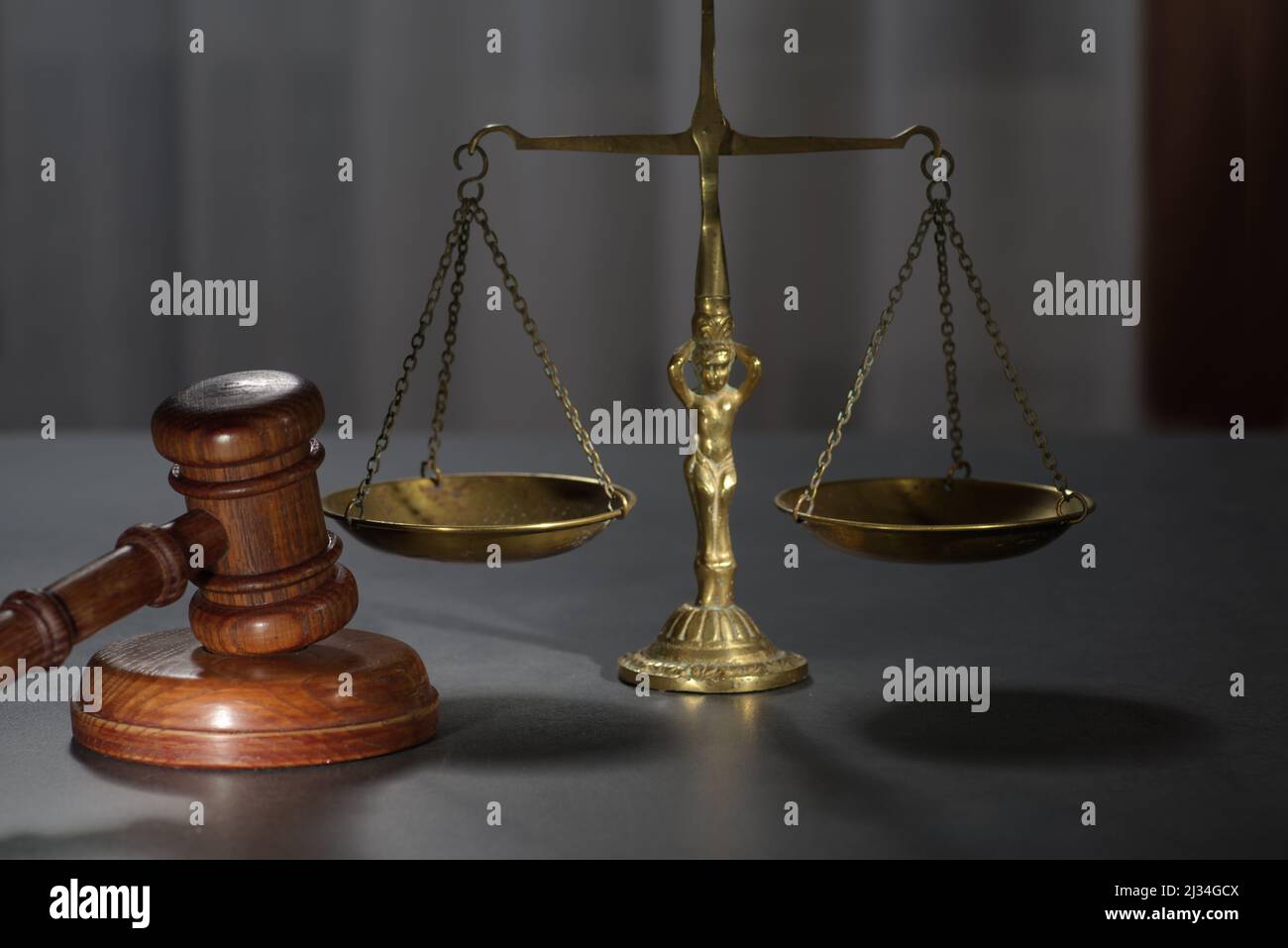 Wooden judges gavel and symbol of law and justice on table in a courtroom or law enforcement office on dark background Stock Photo