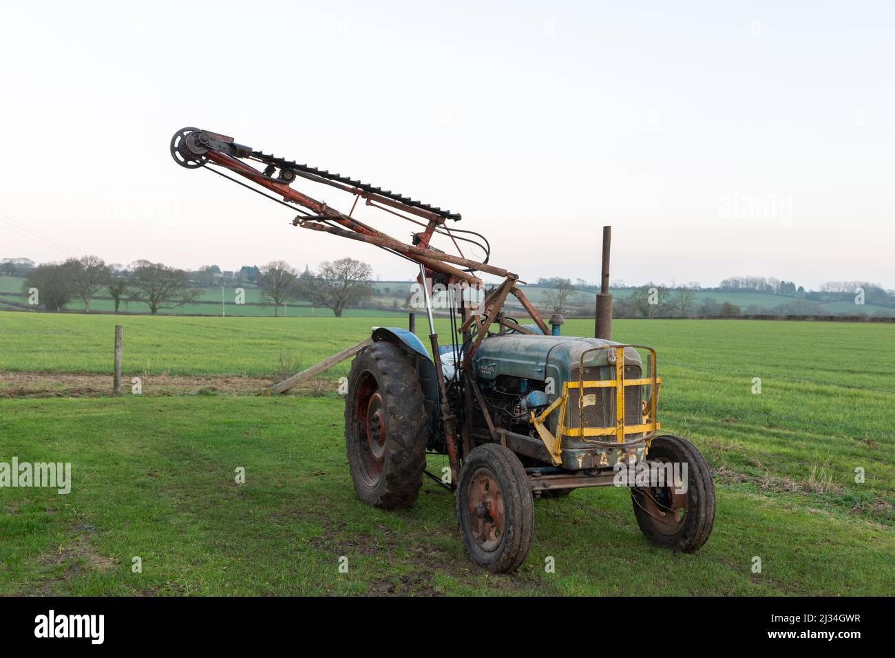 An old antique hedge trimmer mounted on a vintage tractor Stock Photo