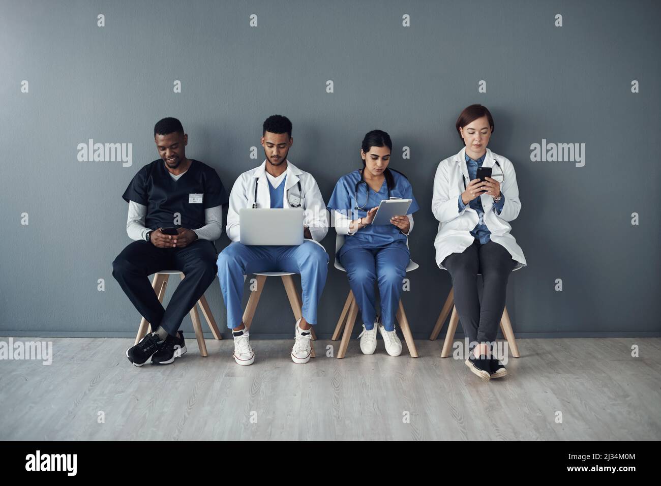 Sometimes, doctors risk their lives just save others. Shot of a group of doctors standing against a grey background at work. Stock Photo