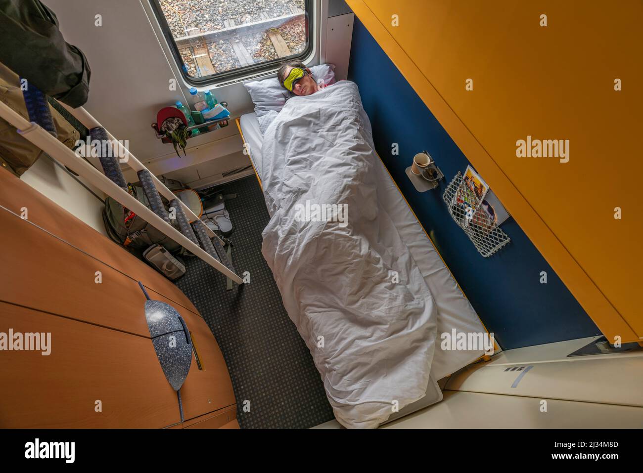 Blue and yellow interior of sleeping coach Prague Zurich with sleeping man Stock Photo