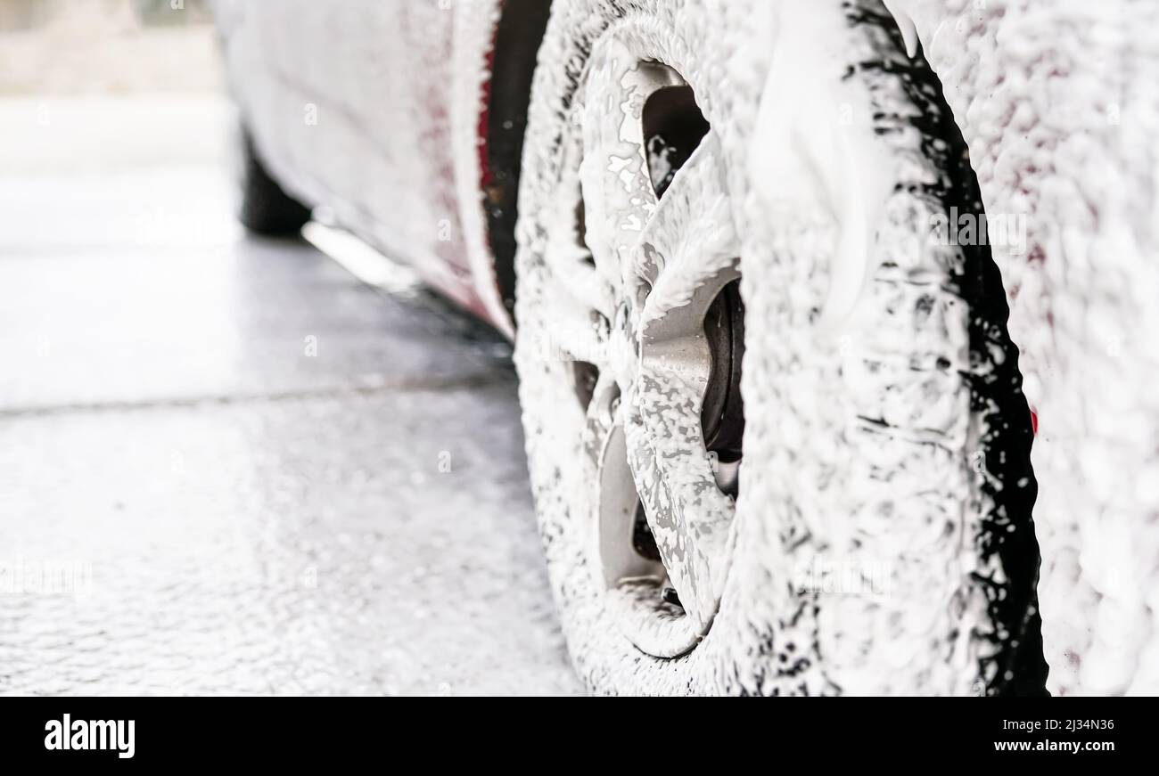 Detail on car wheel covered with lot of soap and shampoo foam, when
